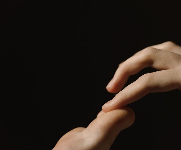 Close-up of a person's hands in a meditative gesture.